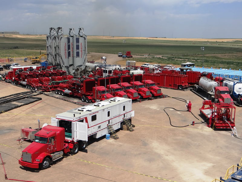 A large assortment of red trucks and machinery organized on a work site surrounded by fields.
